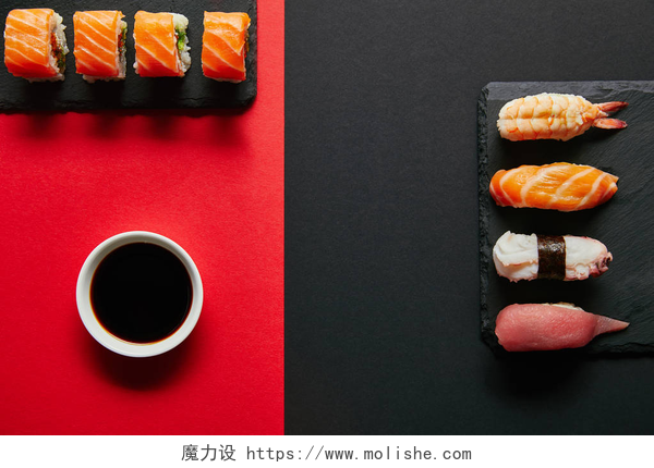 红黑色背景下的三文鱼寿司平躺与酱油在碗里, 寿司套上黑色石板板上的红色和黑色背景